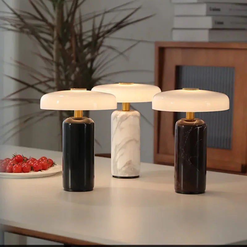 Les trois coloris de la lampe Églantine, marbre noir, blanc et rouge, sur une table de salle à manger